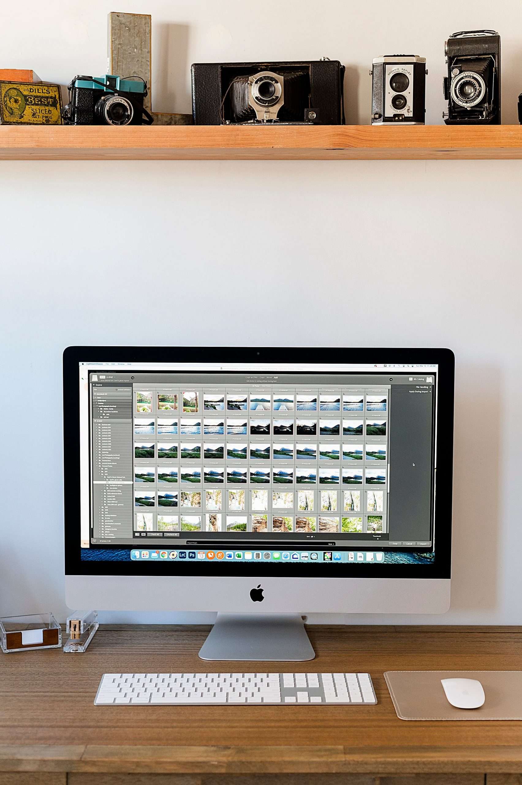 photo showing a desk with adobe Lightroom on monitor and shelf with cameras
