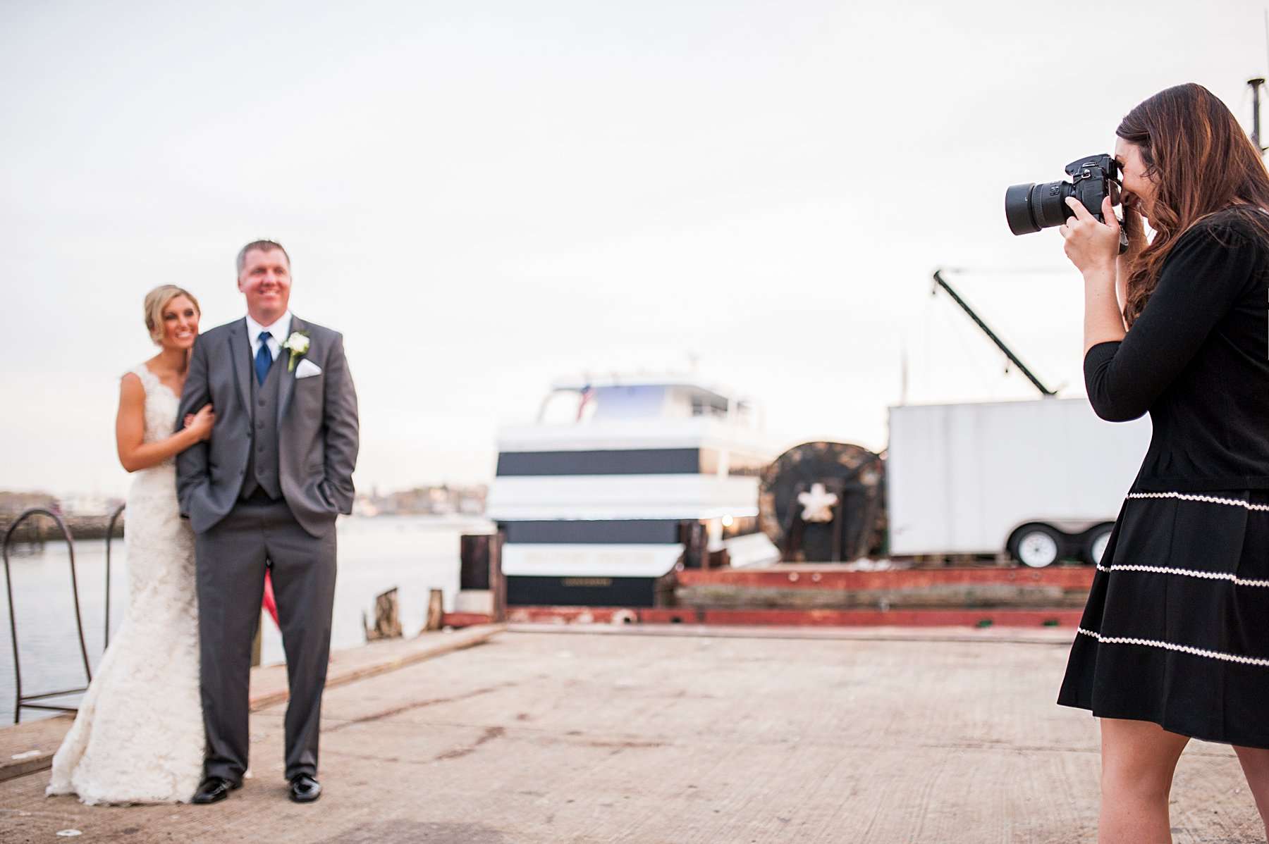A wedding photographer captures a bride and groom by the waterfront. Demonstrating real-life technique in how to find your dominant eye in photography during portrait sessions.