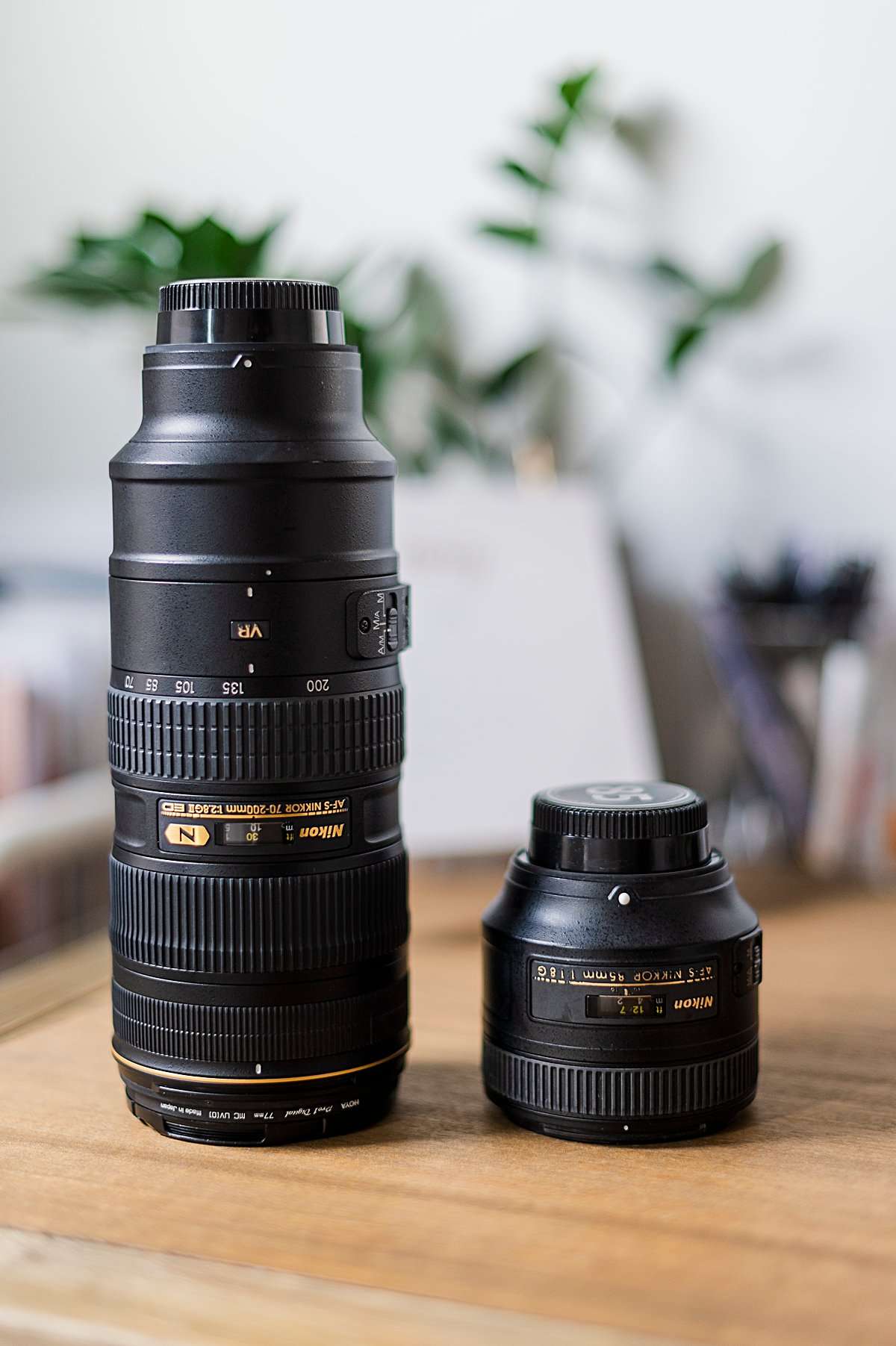 Side-by-side comparison of a bulky Nikon 70-200mm zoom lens and a compact 85mm prime lens. Illustrating size and simplicity differences for why I stopped using zoom lenses.
