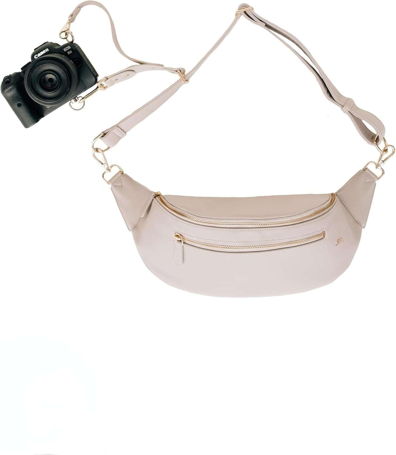 Compact tan leather crossbody camera bag with gold zippers and an adjustable strap connected to a camera. The slim crescent shaped design blends fashion and function, fitting naturally into collections of stylish camera bags for women.