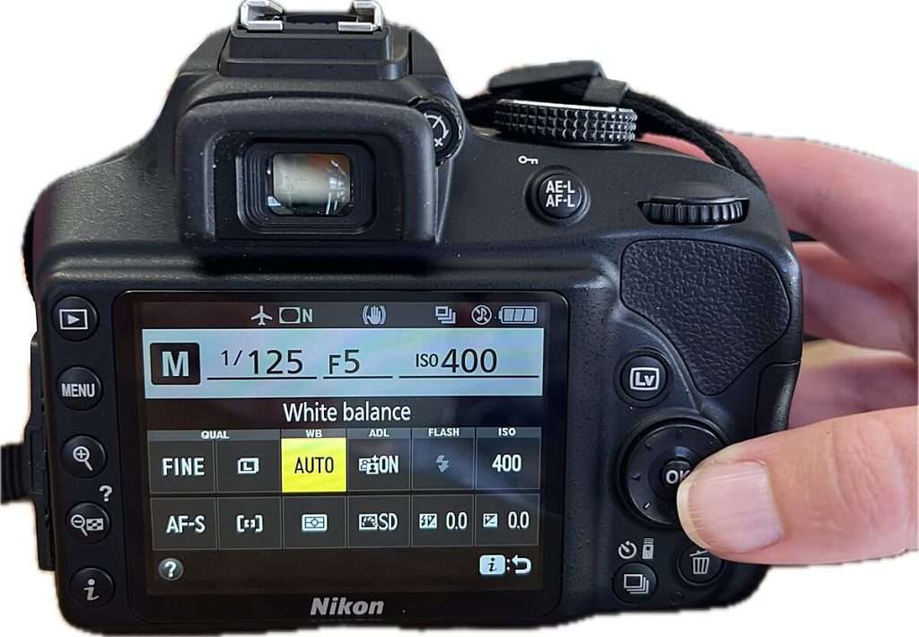 Back of a Nikon camera showing white balance menu set to "AUTO" on the screen with control buttons visible, illustrating basic camera settings for beginners.